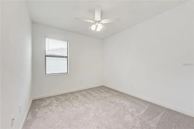 an empty room with a window and a fan