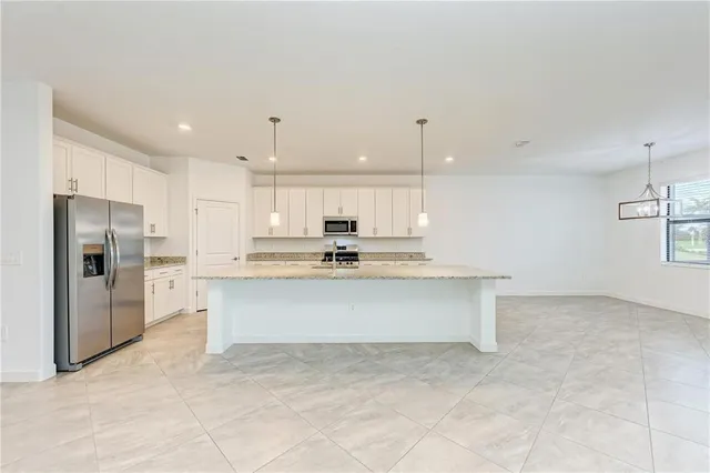 a view of kitchen with refrigerator stove and cabinets