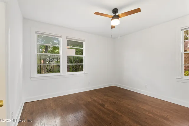 an empty room with a window and a ceiling fan