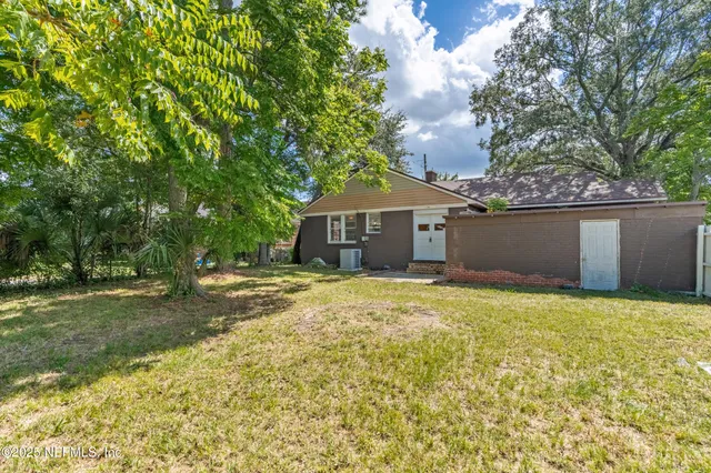 a view of a house with backyard and tree