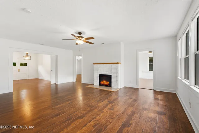 a view of an empty room with a fireplace and wooden floor