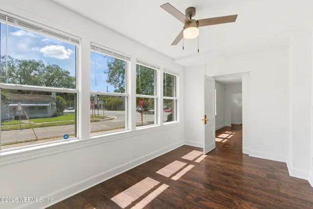 a view of an empty room with a window and wooden floor