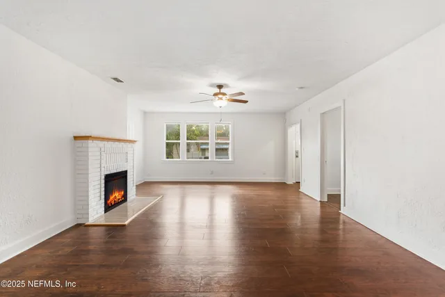 a view of an empty room with a fireplace and a window