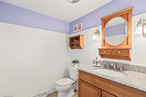 a bathroom with a granite countertop toilet sink and mirror