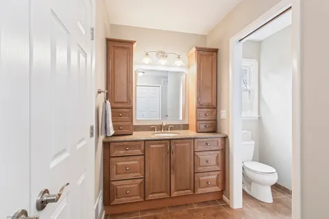 a bathroom with a granite countertop sink toilet a mirror and shower
