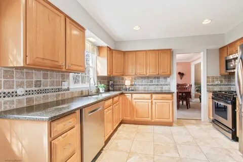 a kitchen with stainless steel appliances granite countertop a stove top oven a sink a counter space and cabinets