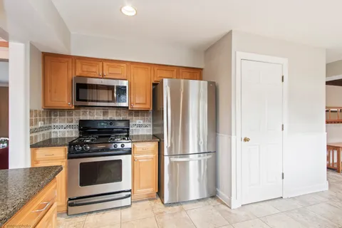 a kitchen with granite countertop a refrigerator stove and microwave