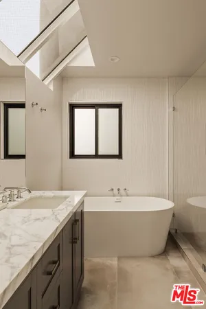 a spacious bathroom with a tub sink and mirror
