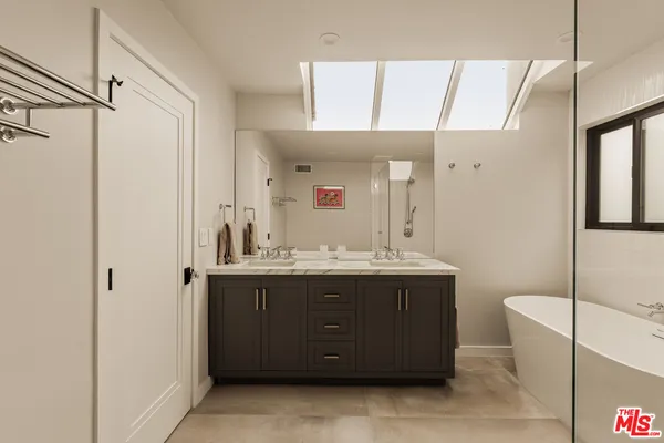 a bathroom with a sink and mirror with bathtub