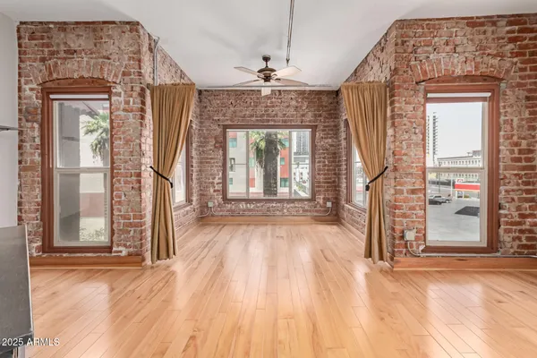 an empty room with wooden floor fireplace and windows