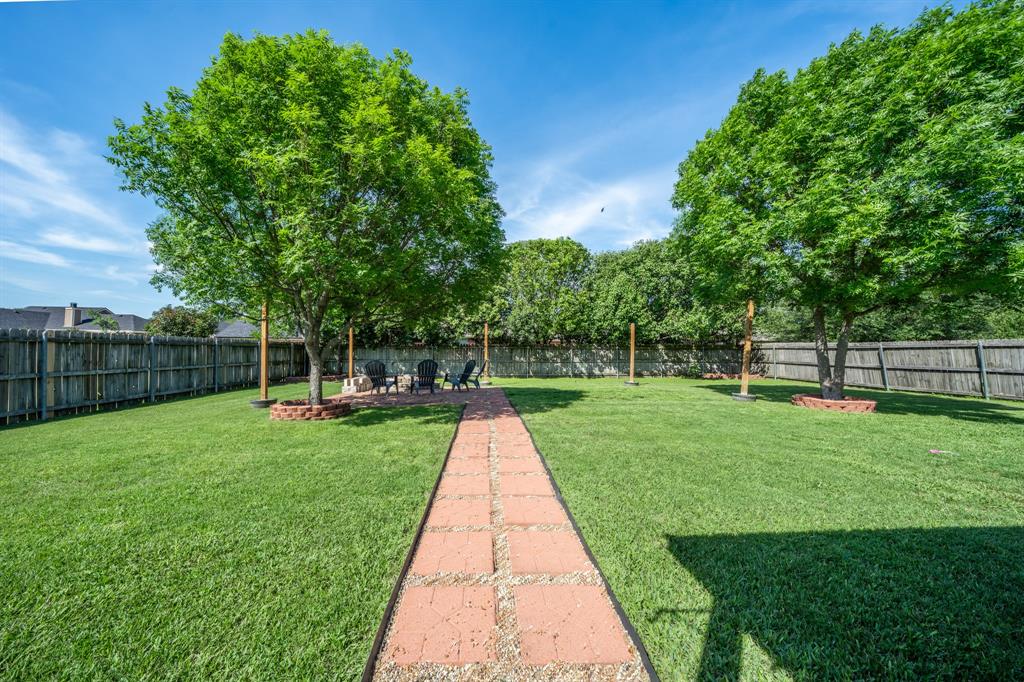 10512 Whitney Trace Drive Waco, TX 76708 - Photo 4 of 39 Expansive backyard featuring a brick paver pathway, lush green lawn, mature trees, and a privacy fence