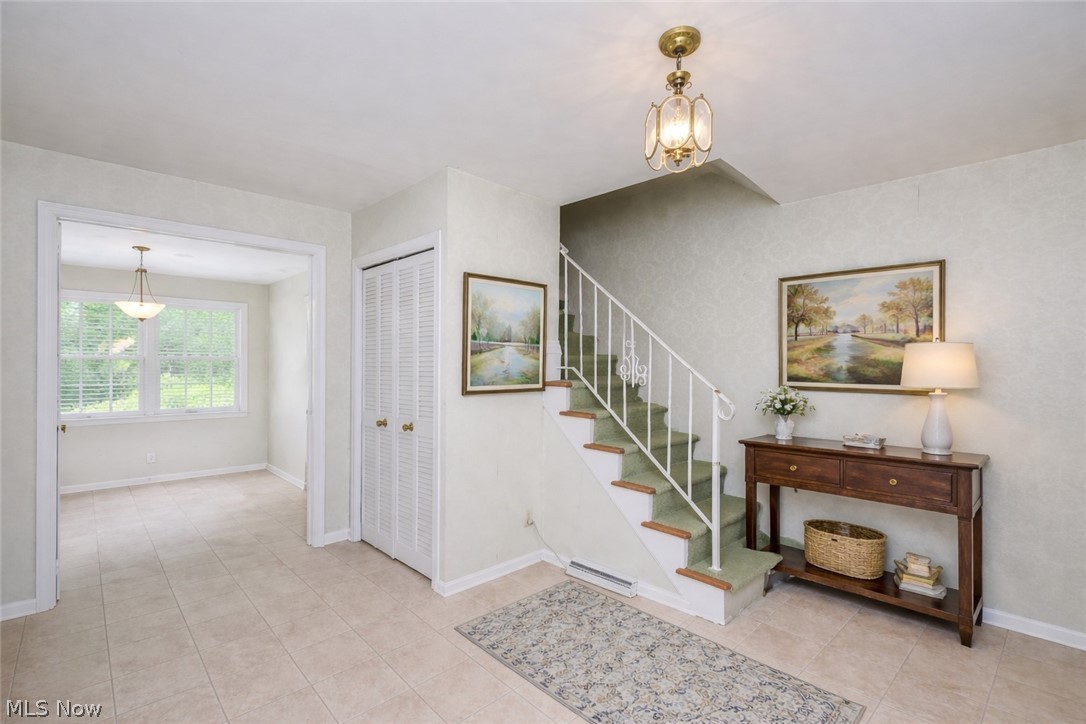 365 Sand Run Road Akron, OH 44313 - Photo 4 of 22 Entry foyer featuring ceramic tile flooring, a staircase with a white railing, and a coat closet with bifold doors