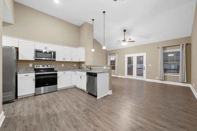 a kitchen with granite countertop wooden floors stainless steel appliances and sink