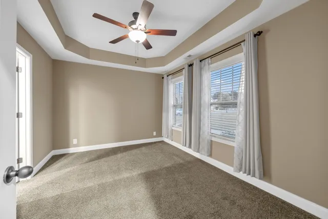 an empty room with windows and fan