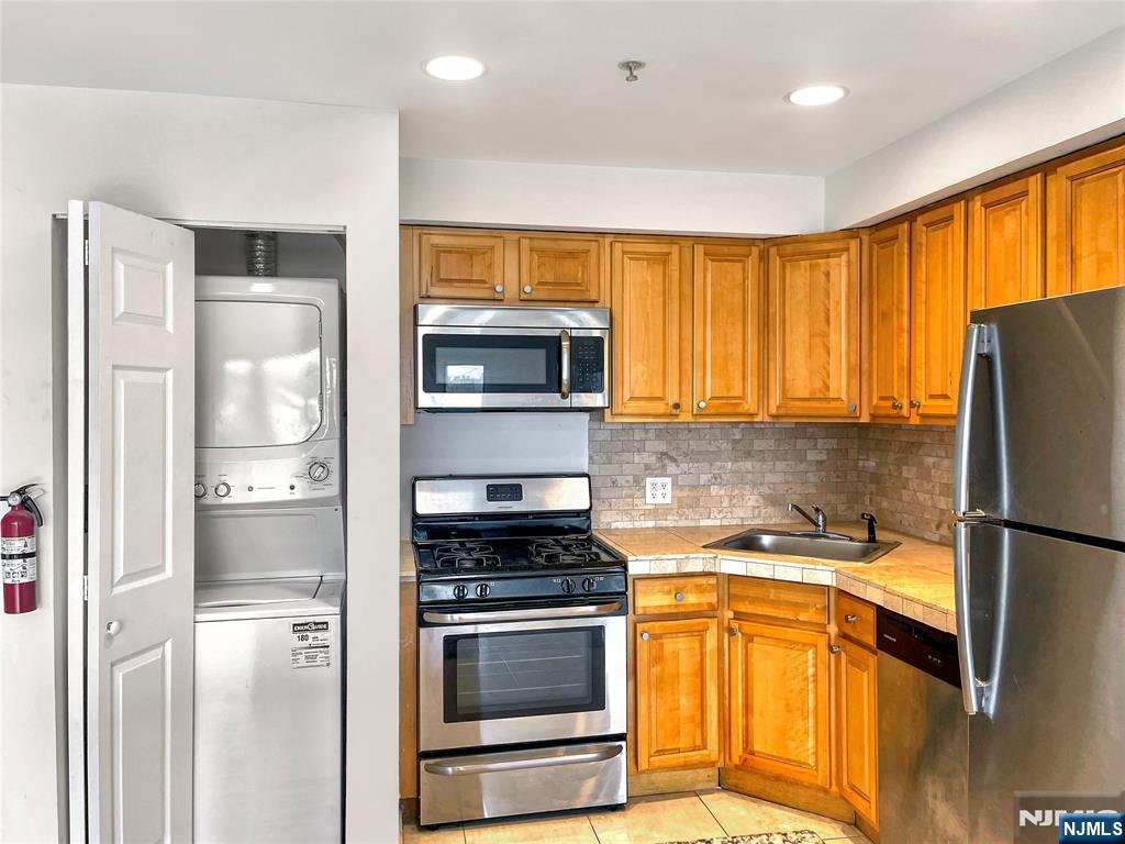 8913 Riverside Place, Unit 3 North Bergen, NJ 07047 - Photo 7 of 17 a kitchen with a refrigerator a stove a sink and a window