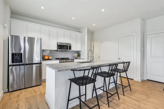 a kitchen with stainless steel appliances a microwave a stove a refrigerator and a dining table