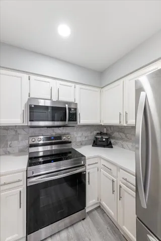 a kitchen with stainless steel appliances white cabinets and a stove top oven