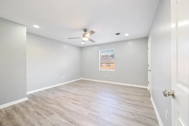 an empty room with wooden floor and windows
