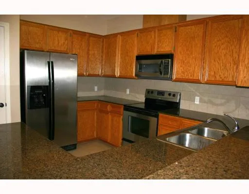a kitchen with stainless steel appliances granite countertop a refrigerator a stove and a sink with wooden floor