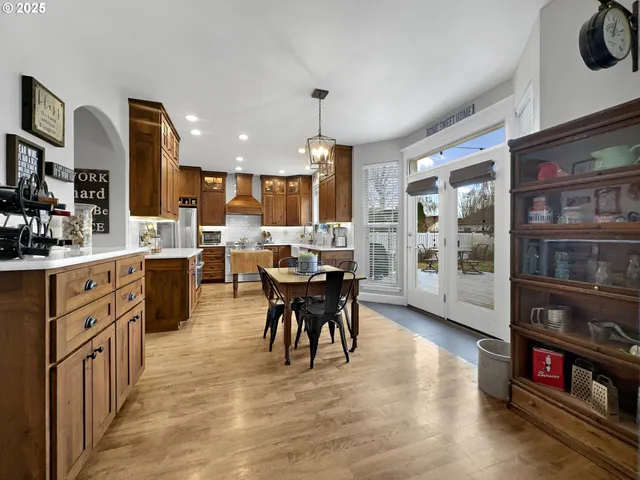 a kitchen with stainless steel appliances kitchen island granite countertop a stove top oven a sink a dining table and chairs with wooden floor