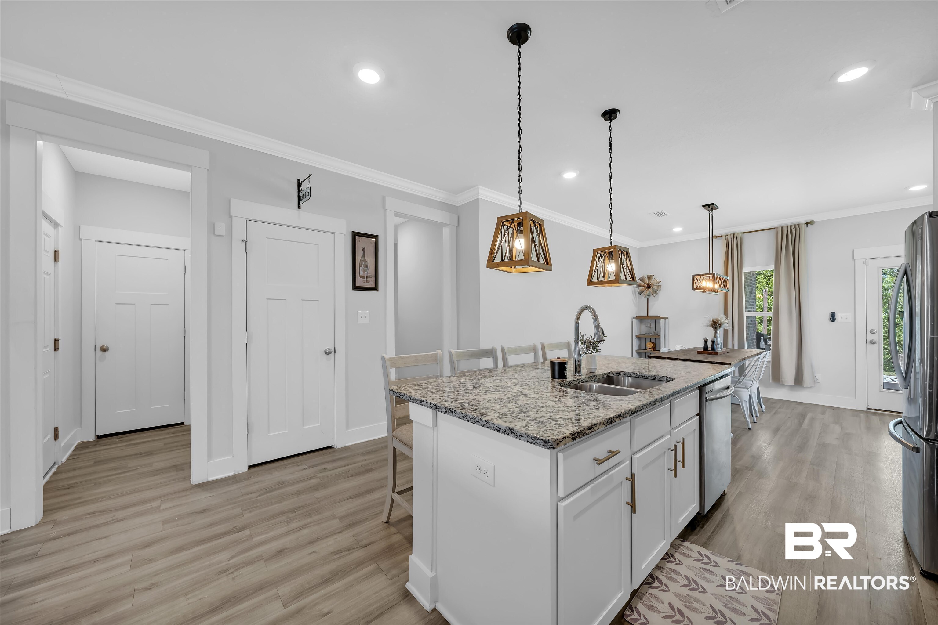 16504 Prado Loop Loxley, AL 36551 - Photo 15 of 45 Kitchen featuring a breakfast bar area, light stone counters, a kitchen island with sink, white cabinetry, and crown molding