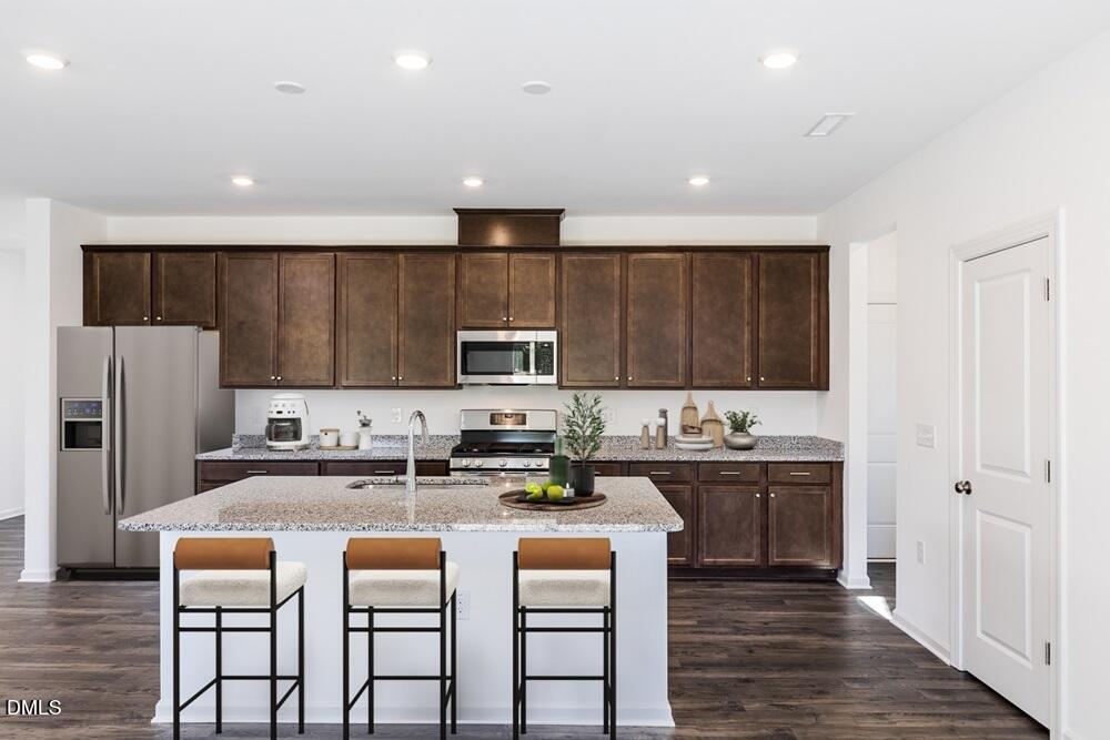 247 Blue Butterfly Drive Angier, NC 27501 - Photo 7 of 41 a kitchen with stainless steel appliances kitchen island granite countertop a refrigerator a stove top oven a sink and cabinets