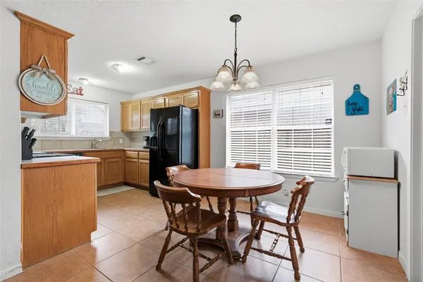 a kitchen with stainless steel appliances granite countertop a refrigerator a stove a sink dishwasher a dining table and chairs with wooden floor