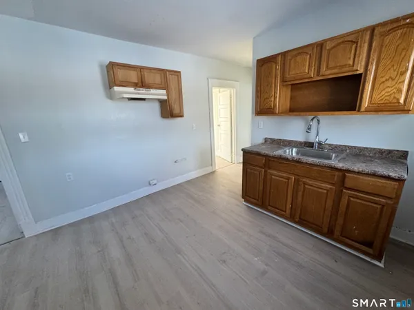 a kitchen with wood cabinets a sink and a stove with wooden floor
