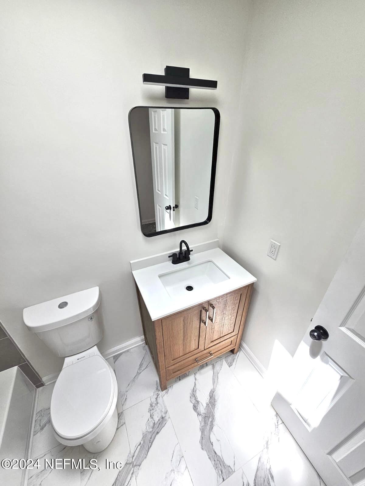 7504 Wheat Road Jacksonville, FL 32244 - Photo 15 of 31 a bathroom with a toilet a sink and mirror