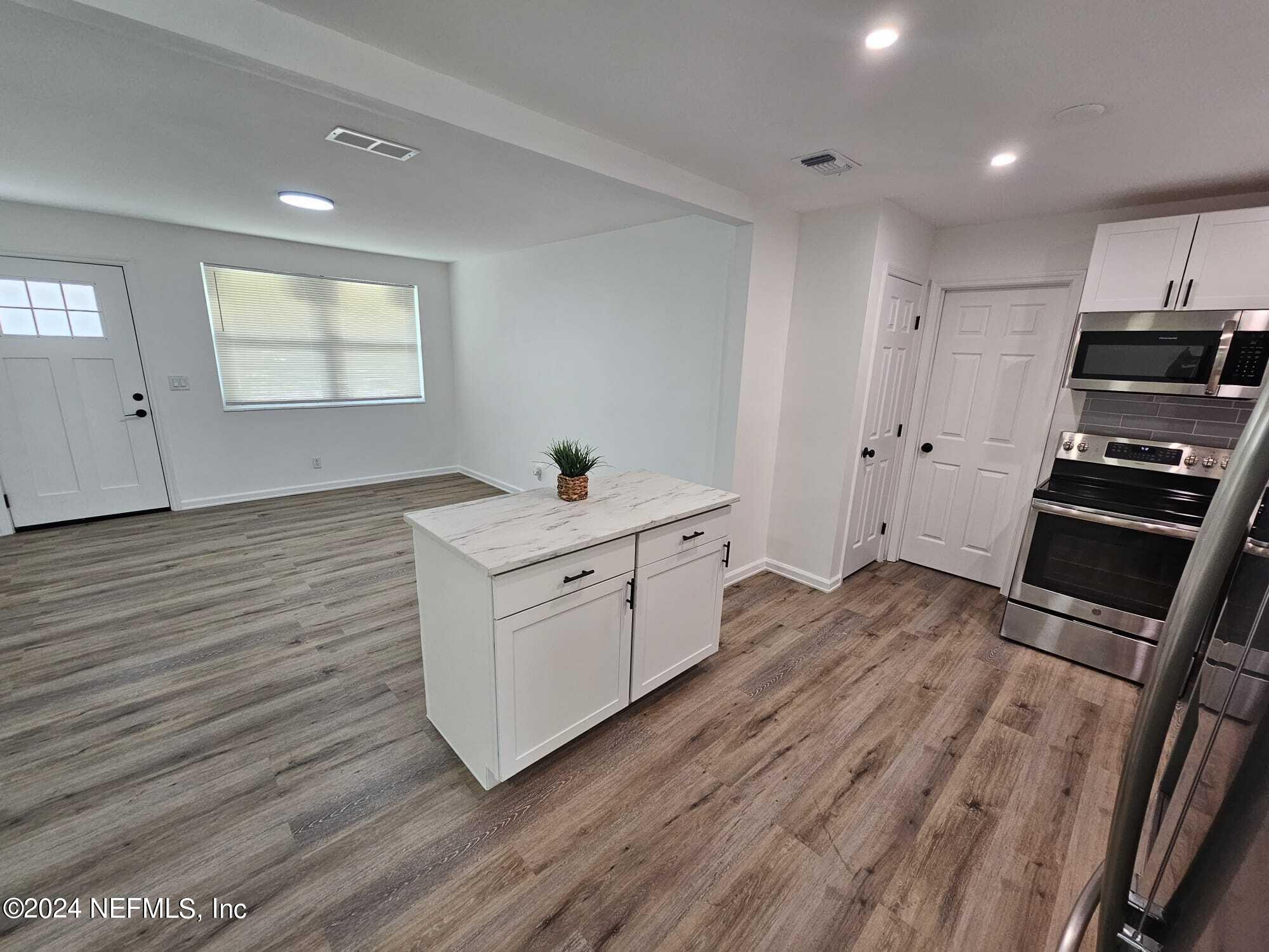 7504 Wheat Road Jacksonville, FL 32244 - Photo 19 of 31 a kitchen with wooden floor and electronic appliances