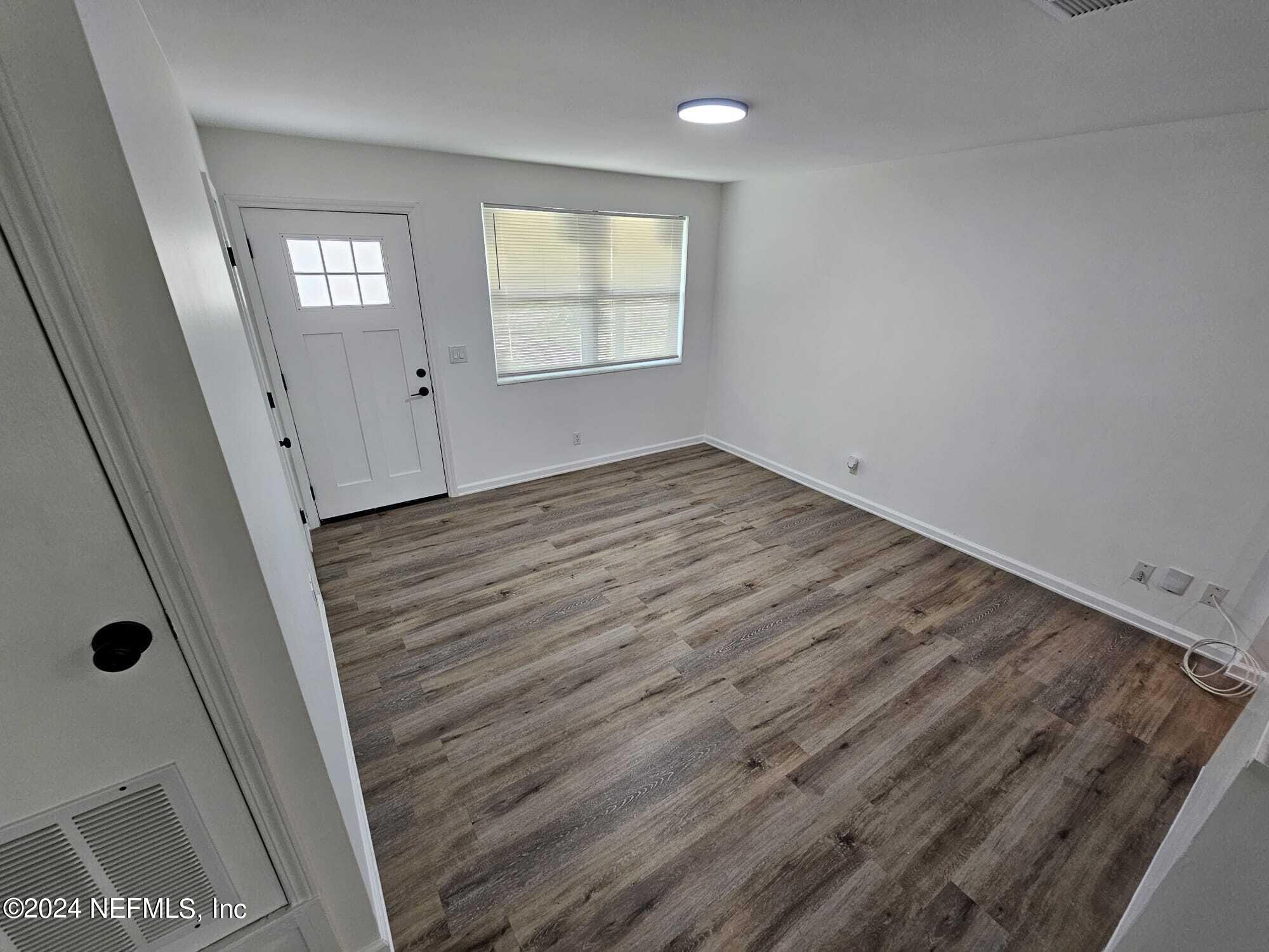 7504 Wheat Road Jacksonville, FL 32244 - Photo 9 of 31 an empty room with wooden floor and windows