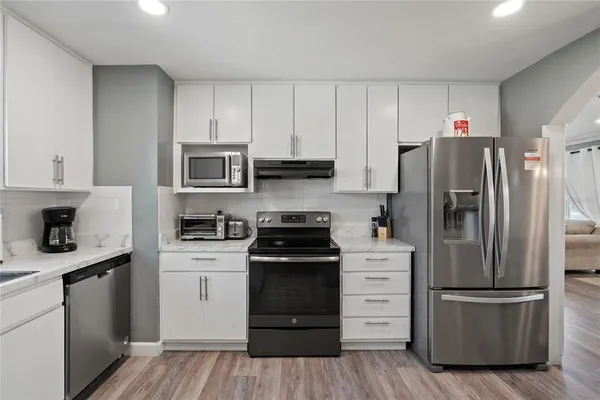 a kitchen with a refrigerator stove and white cabinets