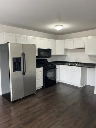 a kitchen with stainless steel appliances wooden cabinets and wooden floor