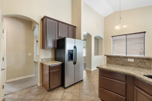 a kitchen with stainless steel appliances granite countertop a stove top oven a sink dishwasher a refrigerator and a oven with wooden cabinets
