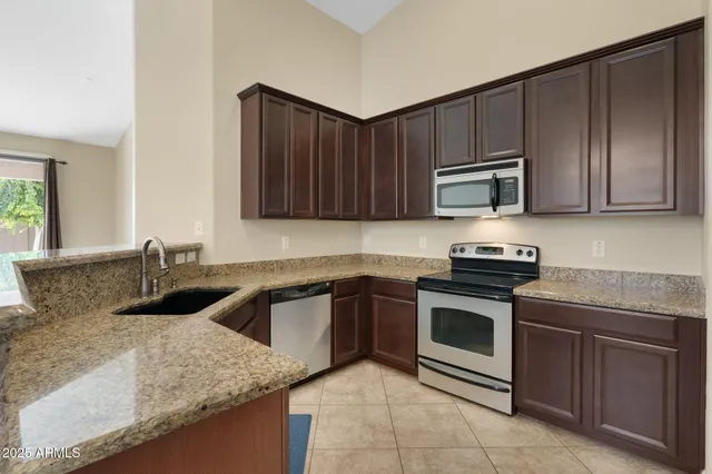 a kitchen with stainless steel appliances granite countertop a stove top oven a sink dishwasher a refrigerator and a oven with wooden cabinets