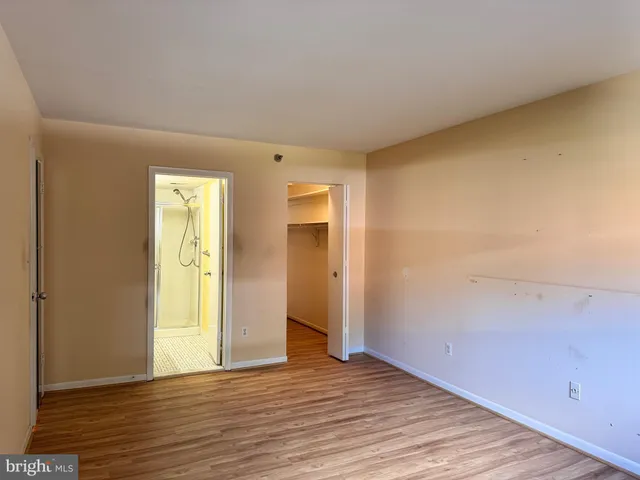 a view of an empty room with wooden floor and closet