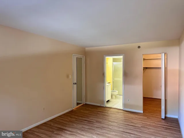 a view of an empty room with wooden floor and closet