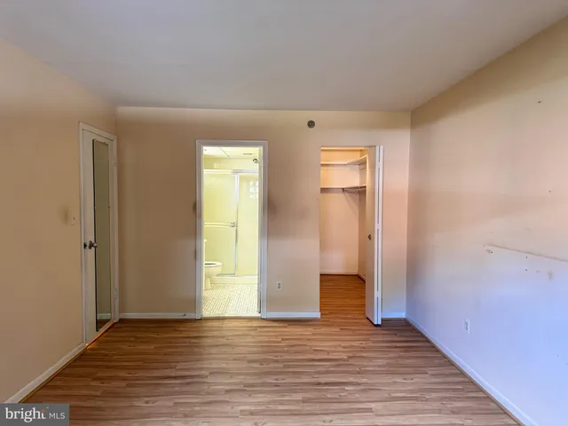 a view of an empty room with wooden floor and closet