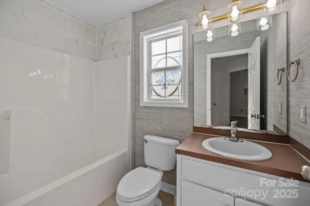 a bathroom with a granite countertop sink a toilet and a mirror