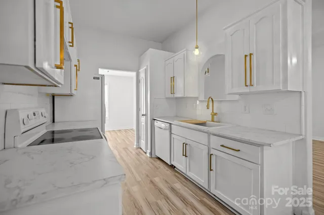 a large white kitchen with granite countertop a sink