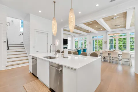 a view of a hallway with wooden floor and a kitchen space