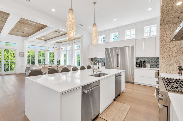 a view of a hallway with wooden floor and a kitchen space