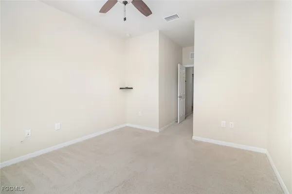 an empty room with a fan & a window