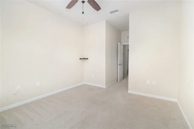 an empty room with a fan & a window