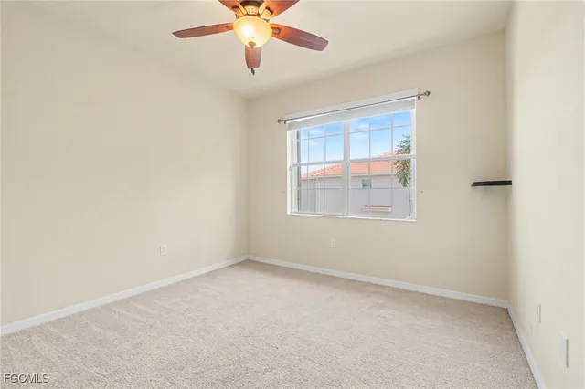 an empty room with a window and a fan