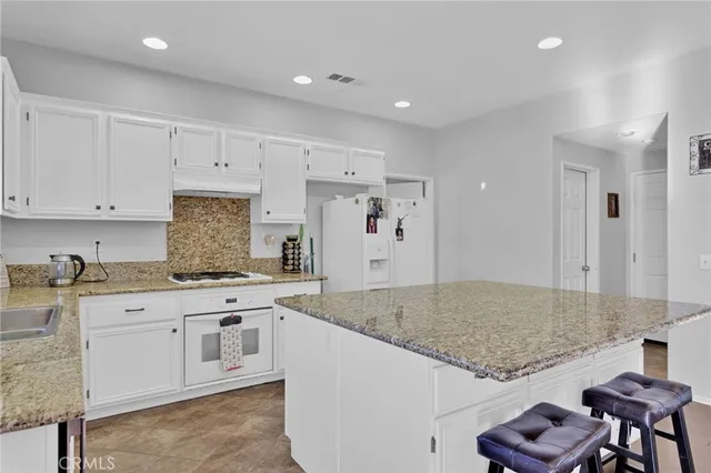 a large kitchen with kitchen island a sink stove and white cabinets