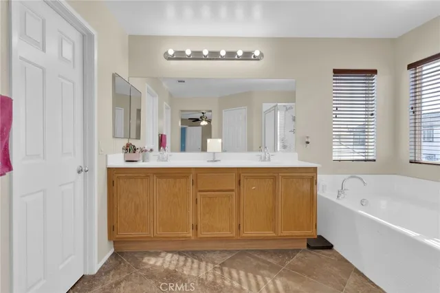 a bathroom with a tub a sink and a large mirror