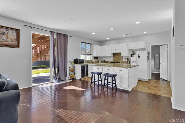 a kitchen with stainless steel appliances granite countertop a refrigerator a stove top oven and a dining table with wooden floor