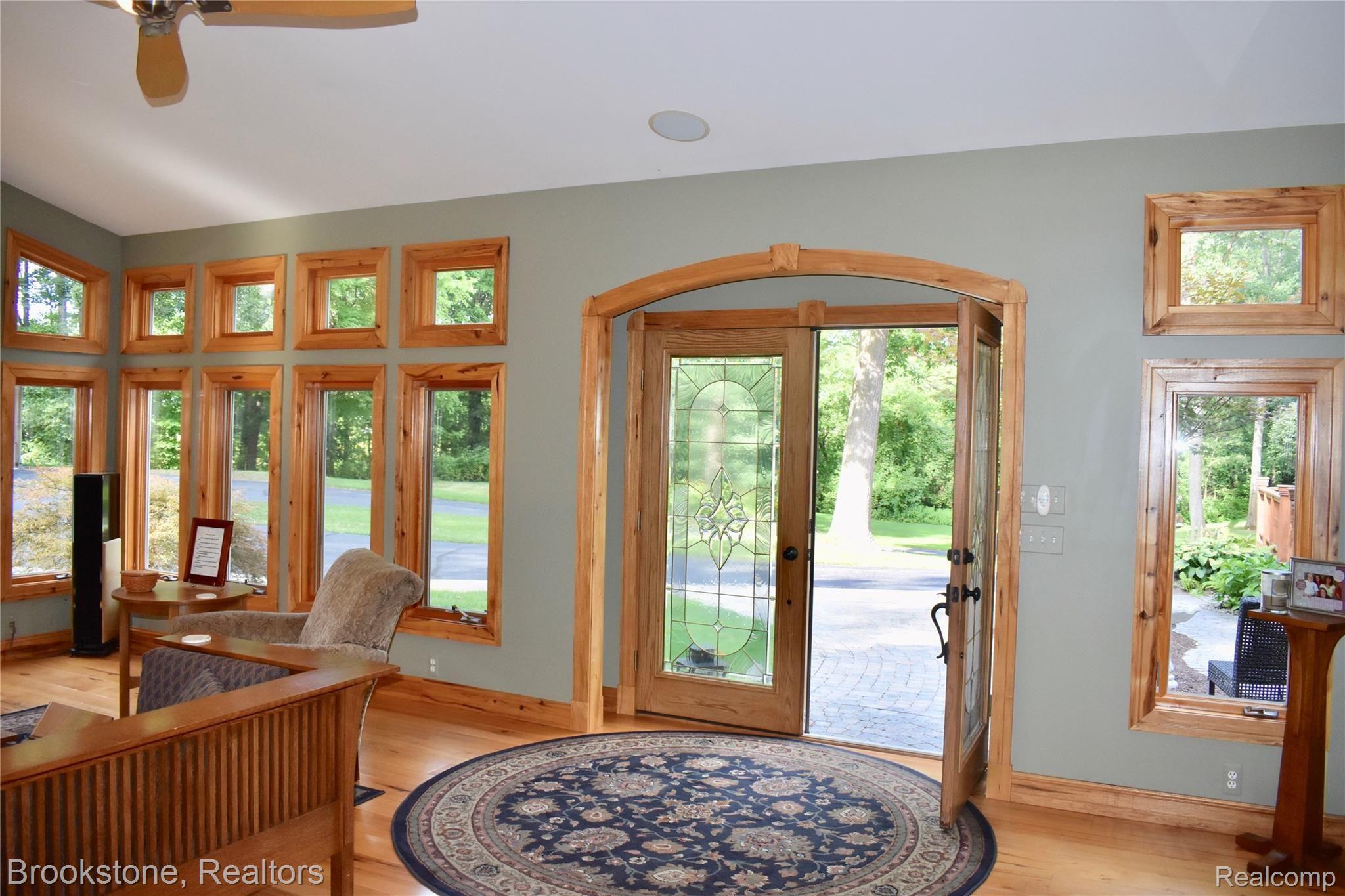 405 Baldwin Ridge Oxford, MI 48371 - Photo 23 of 54 THE LATEST ADDITION WAS THE LARGE GREAT ROOM (19X23) THAT YOU ENTER THROUGH THE FRONT DOUBLE LEADED GLASS DOORS. THE GREAT ROOM WAS DESIGNED THROUGH THE INSTALLATION OF 16 WINDOWS TO FEEL OPEN TO THE WOODS SURROUNDING THE PROPERTY
