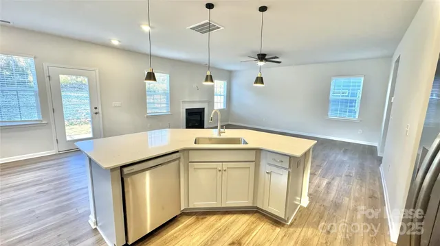 a kitchen with stainless steel appliances granite countertop a sink a microwave oven a refrigerator and wooden floor